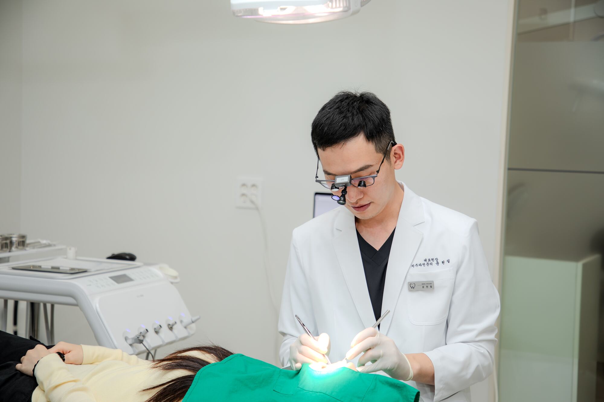 윤현필 대표원장이 진료 의자에 누운 환자를 확대경을 쓰고 진료하는 모습