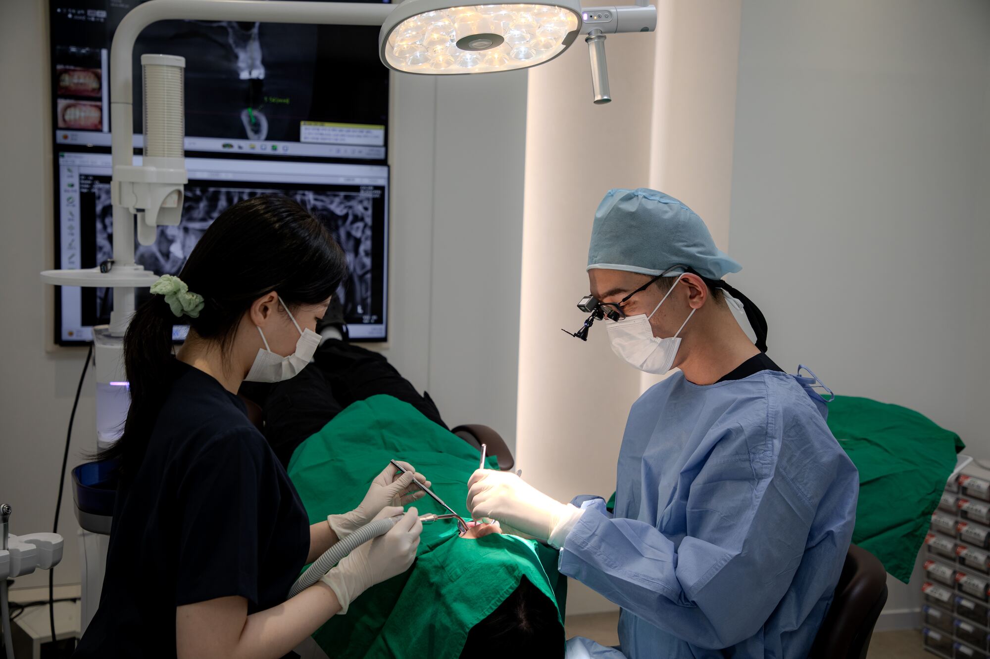CT로 임플란트 식립 계획을 띄워 두고 윤현필 대표원장과 치위생사가 수술하는 모습